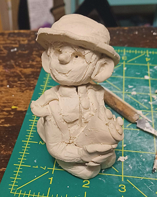 Unpainted clay sculpture of a WW1 british soldier holding a bouquet of flowers